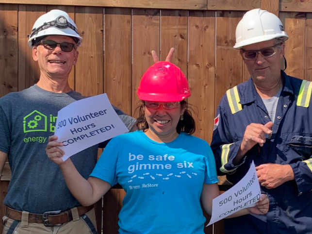 Byron takes a goofy pic with a homeowner holding a sign that says 500 volunteer hours completed!!