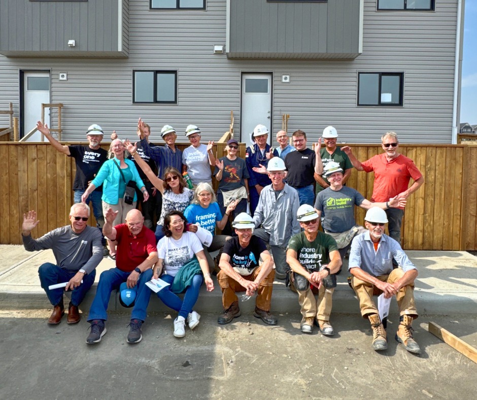Volunteer Crew Leaders take a group photo in front of Calgary's Livingston24 homes.