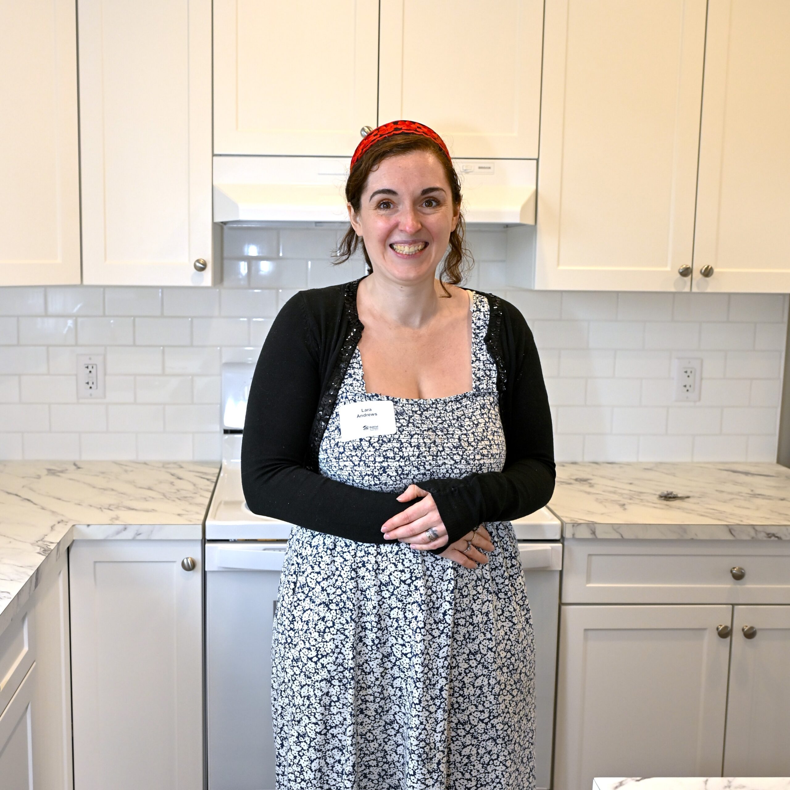 Habitat homeowner Lara stands in an all white kitchen.