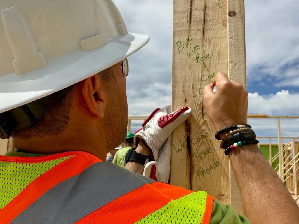 An Ovintiv employee signs a lumber stud with a message of support.