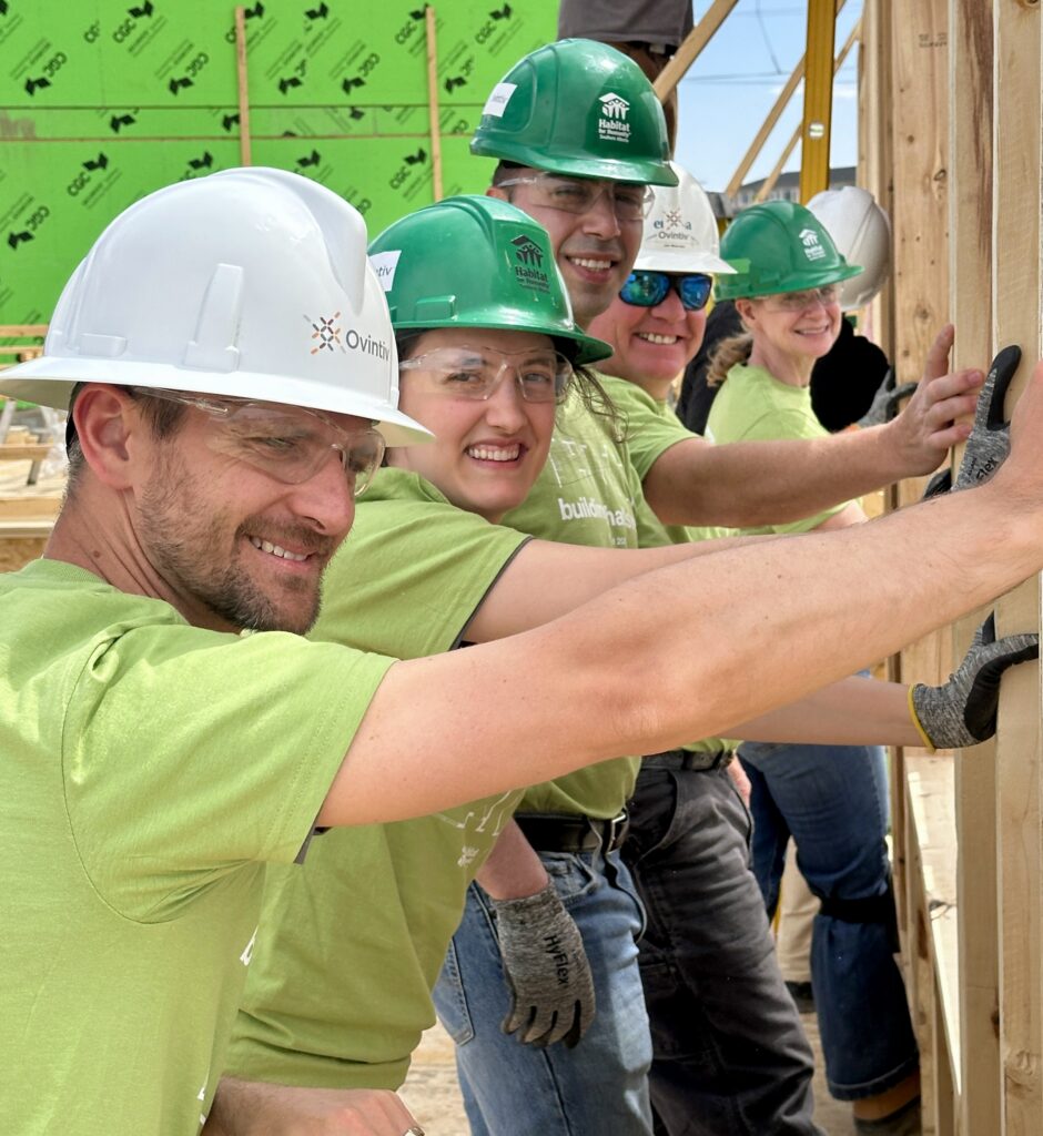 Five Ovintiv employees work together to raise a framed wall.